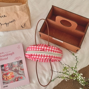 Macro shot of red gingham fabric tote bag with fine embroidery and leather handle