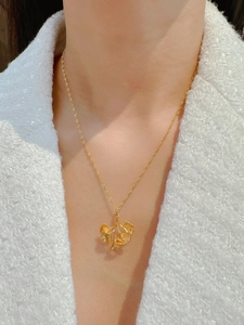 Macro shot of gold-plated ginkgo leaf pendant necklace on a white tweed garment