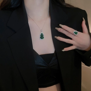 Close-up of green gourd pendant and heart ring set with zircons on a model
