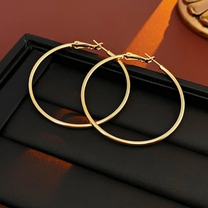 Close-up of gold hoop earrings on a black leather tray with warm lighting effects