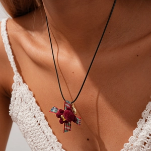 Detail of burgundy plush pendant necklace with red-green plaid ribbon and gold bow