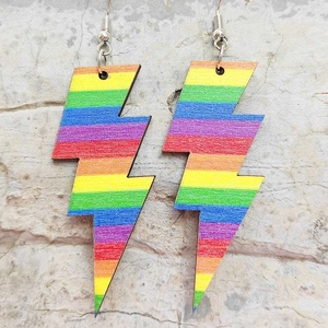 Macro detail of lightning bolt drop earrings with vibrant rainbow stripes on textured stone
