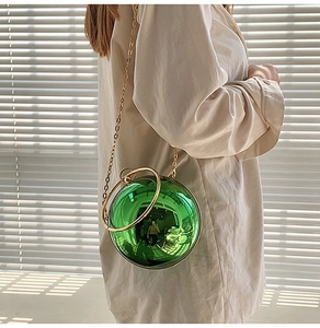 Dettaglio di una borsa a sfera in acrilico verde con manico dorato e catena sottile