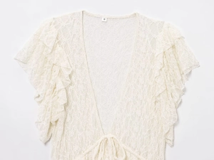 Gros plan d'une blouse en dentelle blanche avec motifs floraux et nœud de cravate au col