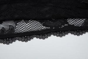 Détail du tissu en dentelle florale noire avec motifs en maille et bordures festonnées