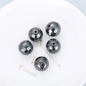 Macro shot of 5 faceted dark gray hematite beads with metallic luster on white tray