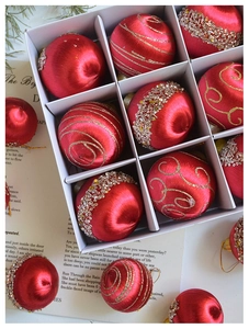 Makroaufnahme roter Satin-Weihnachtskugeln mit Goldglitzer und Silberpailletten im Karton