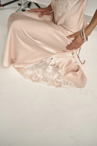 Detail of light pink satin slip dress featuring elegant white lace trim and silky texture