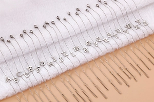 Silver alphabet initial bracelets with rhinestones displayed on a soft textured background
