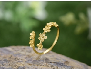 Macro detail of gold-tone floral open ring showcasing intricate flower design on a natural rock