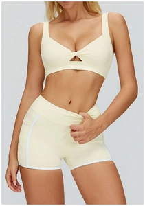 Dettaglio del set yoga crema con reggiseno con incrocio e pantaloncini a vita alta con tasche