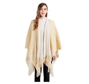 Dettaglio del poncho in maglia beige con eleganti nappe a frange e finitura morbida