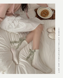 Detail of cream white cotton lolita socks with bow ribbon on a cozy bed background