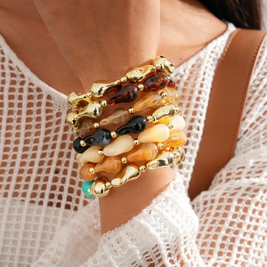 Détail de bracelets ethniques en perles géométriques dorées et ambre sur le poignet