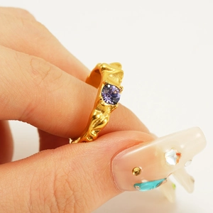 Detail of gold irregular textured ring with purple gemstone in a hand-held close-up shot