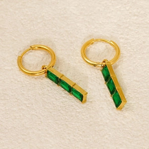 Detailed view of gold hoop earrings with triple rectangular green gemstone pendants