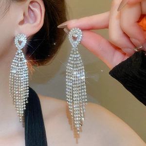 Close-up of sparkling silver tassel earrings with crystal rhinestones on a female model