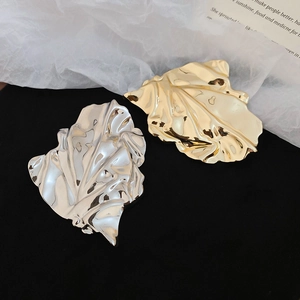 Macro detail of gold and silver irregular leaf brooches with elegant wrinkled metal textures