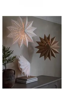Close-up of hanging white and kraft paper star lanterns with warm glowing hollow patterns