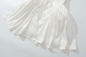 Détail de la robe en satin blanc avec cordon à la taille et ourlet plissé élégant