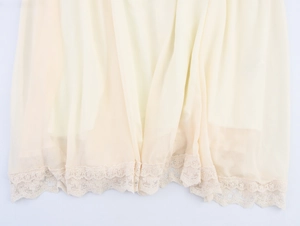 Détail d'une robe en mousseline beige avec un ourlet délicat en patchwork de dentelle