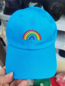 Close-up of vibrant rainbow embroidery on a bright blue twill cotton baseball cap detail
