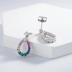 Teardrop hollow silver stud earrings with colorful zirconia stones on white pedestal