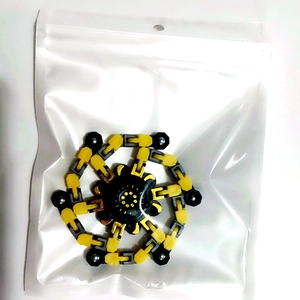 Close-up of a yellow and black fidget chain spinner toy in a transparent poly bag