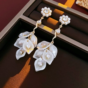 Detailed macro view of gold tassel earrings with pearls and zircons in a jewelry box