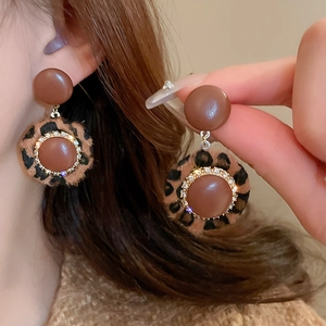 Macro shot of leopard print earrings with rhinestones and vintage brown resin accents