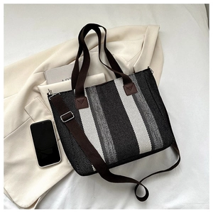Close-up of striped canvas tote bag with woven texture and adjustable shoulder strap