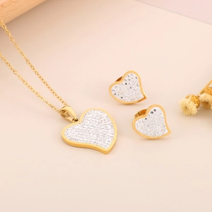 Close-up of gold titanium steel heart jewelry set with sparkling rhinestones on necklace and earrings