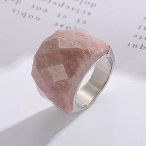 Macro shot of faceted pink raw stone ring with a wide polished silver metal band