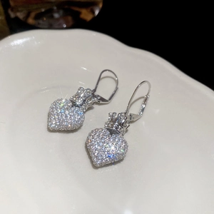 Detailed view of silver heart crown earrings with sparkling zircons on a white display plate