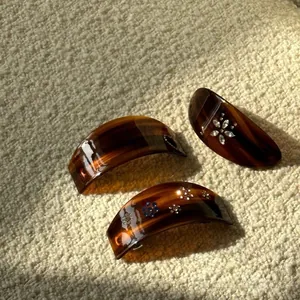 Detail of three acetate hair clips in amber tortoiseshell with elegant rhinestone patterns