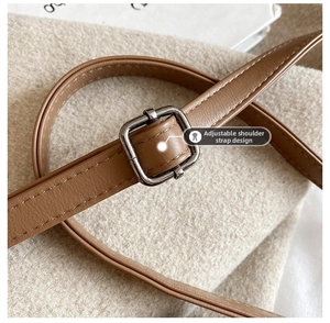 Detail of adjustable brown faux leather shoulder strap with square metal buckle and stitching