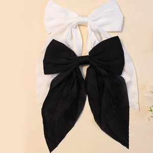 Close-up of black and white textured fabric bow hair clips with long ribbon tails