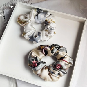 Silk scrunchies with floral prints in white and beige on an elegant tray