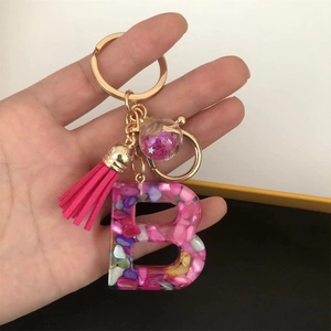 Pink resin letter B keychain with colorful stone chips, tassels and a liquid glitter ball