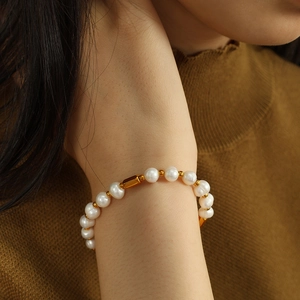 Fashionable freshwater pearl bracelet with gold metal beads worn on wrist over knitwear