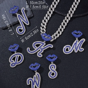 Detail view of iced out Cuban link chain and blue lip letter pendants with size dimensions