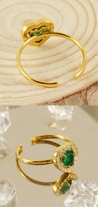 Detailed close-up of heart-shaped green zircon ring with gold plating and open band design