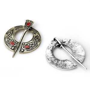Detail of vintage Viking brooches in bronze with red enamel and silver radial texture