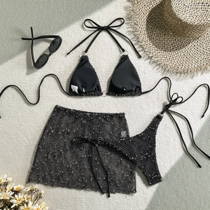 Flat lay of a three-piece black sequin bikini set with mesh skirt and summer accessories