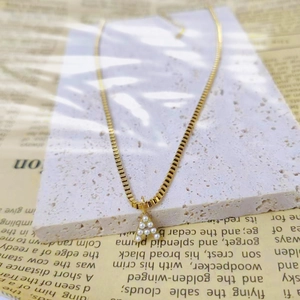 Close-up of a gold titanium steel box chain necklace with a pearl-inlaid letter A pendant.