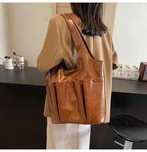 Detail showing the brown leather tote bag side profile with a functional external pocket