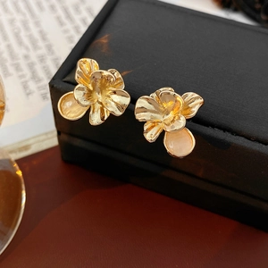 Macro shot of vintage golden flower earrings with brushed texture and cat eye stone detail