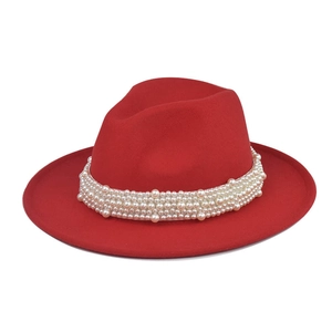 Detalle de sombrero fedora de lana roja con elegante banda decorativa de perlas