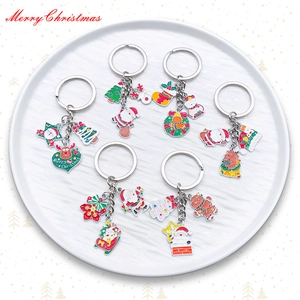 Detail shot of six Christmas enamel keychains featuring Santa and reindeer on a white plate
