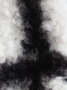 Macro detail of soft black and white plaid plush fabric with resin button on the coat